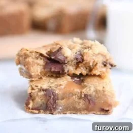 Two salted caramel brown butter chocolate chip bars stacked on each other on white wax paper.