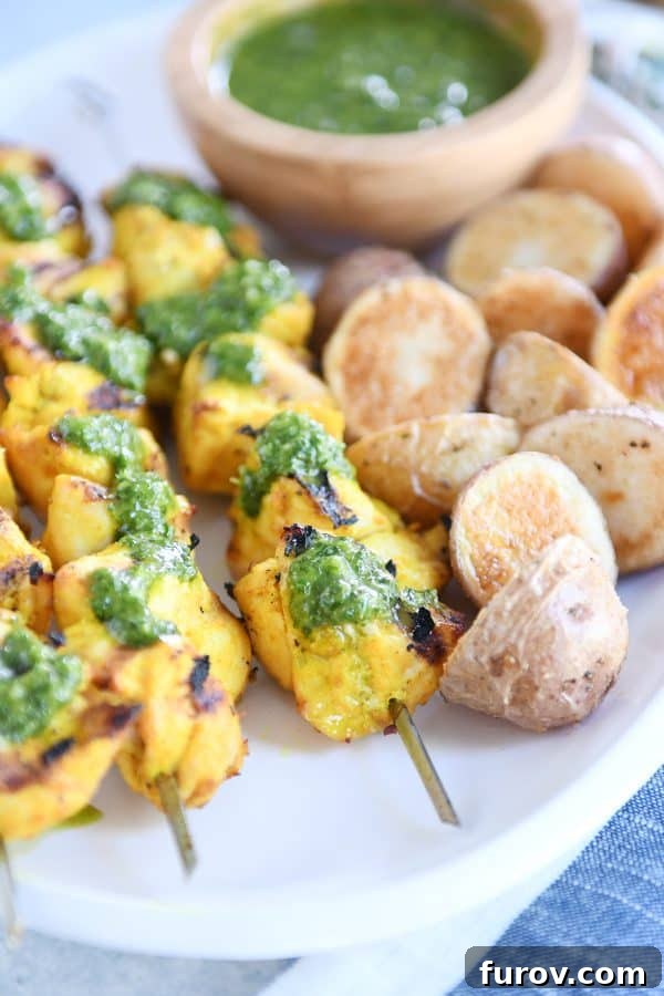 Moroccan Chicken Skewers with Zesty Green Sauce 2 Close up view of green sauce on Moroccan chicken skewer with a couple roasted potatoes, highlighting the vibrant colors.