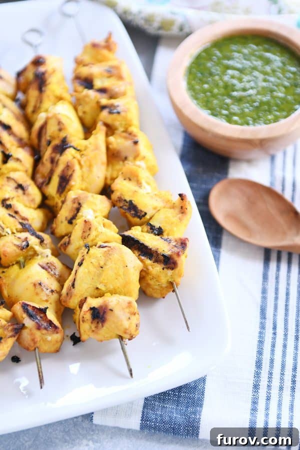 Moroccan Chicken Skewers with Zesty Green Sauce 3 White platter featuring three perfectly grilled Moroccan chicken skewers, ready to be served.
