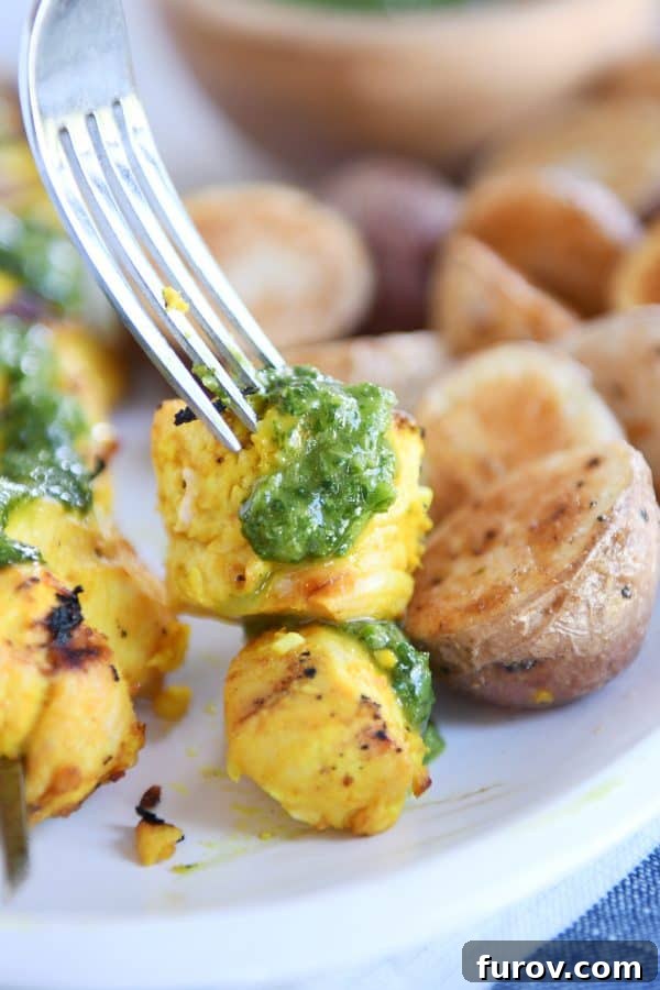 Moroccan Chicken Skewers with Zesty Green Sauce 4 A fork piercing a piece of Moroccan chicken skewer, generously drizzled with the vibrant green sauce.