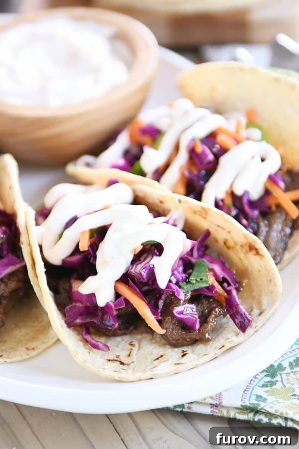 Game Changing Korean Beef Tacos with Zesty Slaw and a Sauce Beyond Compare 2 Irresistible Korean beef tacos with vibrant slaw and a rich sauce, arranged on a pristine white platter.