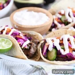 Korean beef tacos with slaw and sauce on white platter.