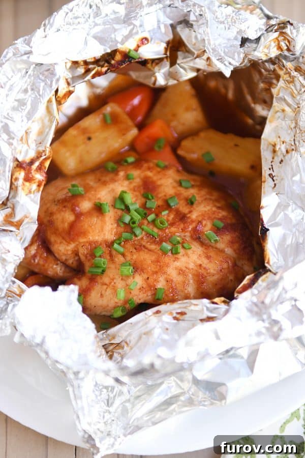 Hawaiian Pineapple Chicken Foil Packs Grilled or Baked 2 BBQ Hawaiian chicken foil packet opened with chicken, peppers and pineapple inside, showcasing the vibrant ingredients.