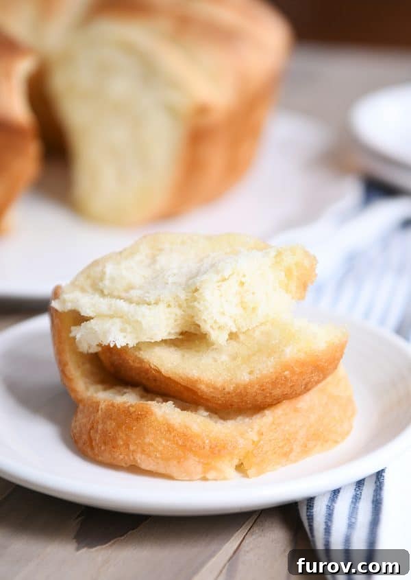 Stack of golden, buttery pull apart bundt bread pieces on a pristine white plate, ready to be enjoyed.