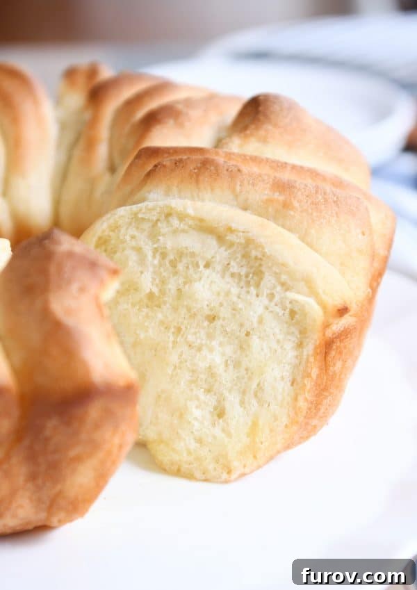 A beautifully golden and rustic pull apart bundt bread, presented on a white platter, inviting diners to tear off a piece.