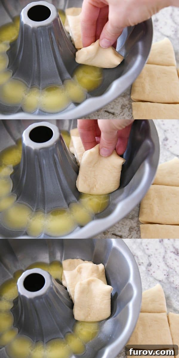 A close-up view of dough pieces being dipped in melted butter and meticulously layered into a bundt pan, demonstrating the assembly process.