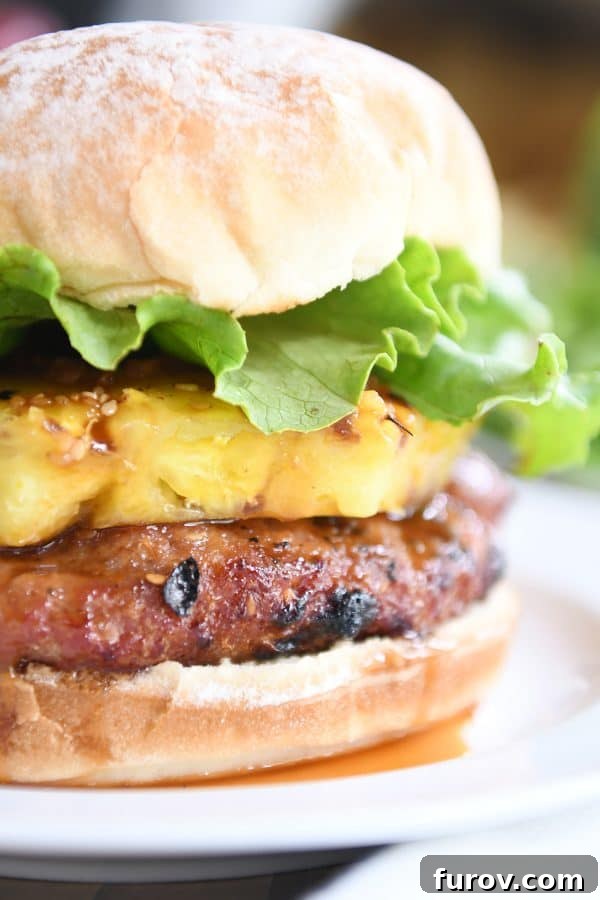 Close up of a teriyaki turkey burger with grilled pineapple, fresh lettuce, and a soft bun, ready to be eaten.