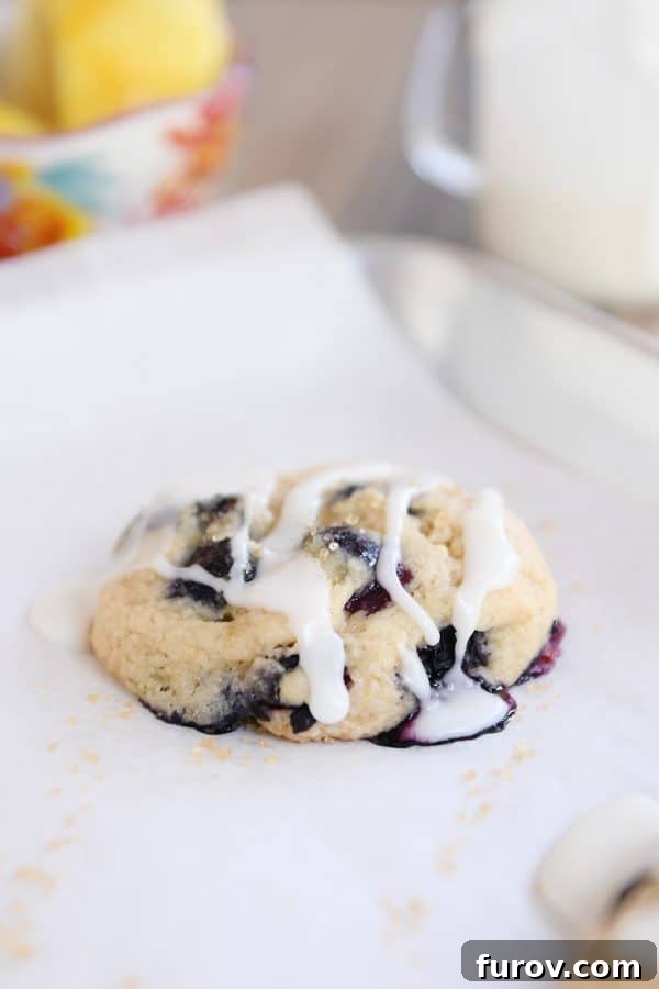 Blueberry Muffin-Top Cookies 9 Glazed blueberry muffin cookie on parchment lined baking sheet.