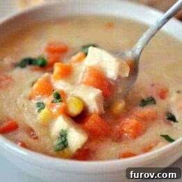 A top-down view of a bowl of Chicken Corn Chowder with Sweet Potatoes, garnished with fresh parsley.