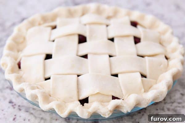 A close-up view of the beautifully fluted edge of a cherry pie crust, ready for baking.