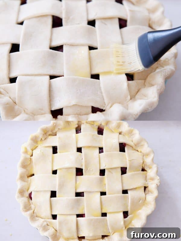 Brushing a beaten egg wash over the golden lattice top crust of an unbaked cherry pie.