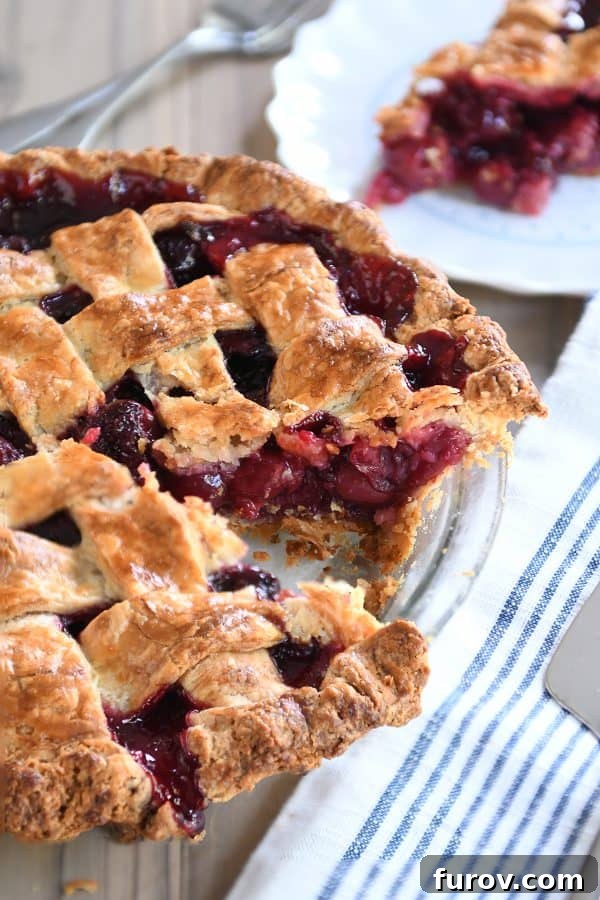 A beautifully baked cherry pie with a slice already served, showcasing the rich cherry filling and golden lattice crust.