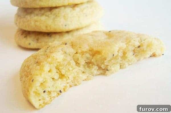 Lemon poppy seed cookie split in half, revealing its soft texture and poppy seeds.