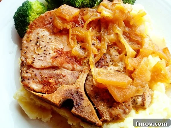 Sweet and Savory Pork Chops with Caramelized Apples and Onions 3 Bone-in pork chop with cooked onions on top.