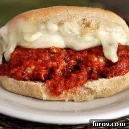 A close-up of a meatball sub, garnished with fresh herbs.