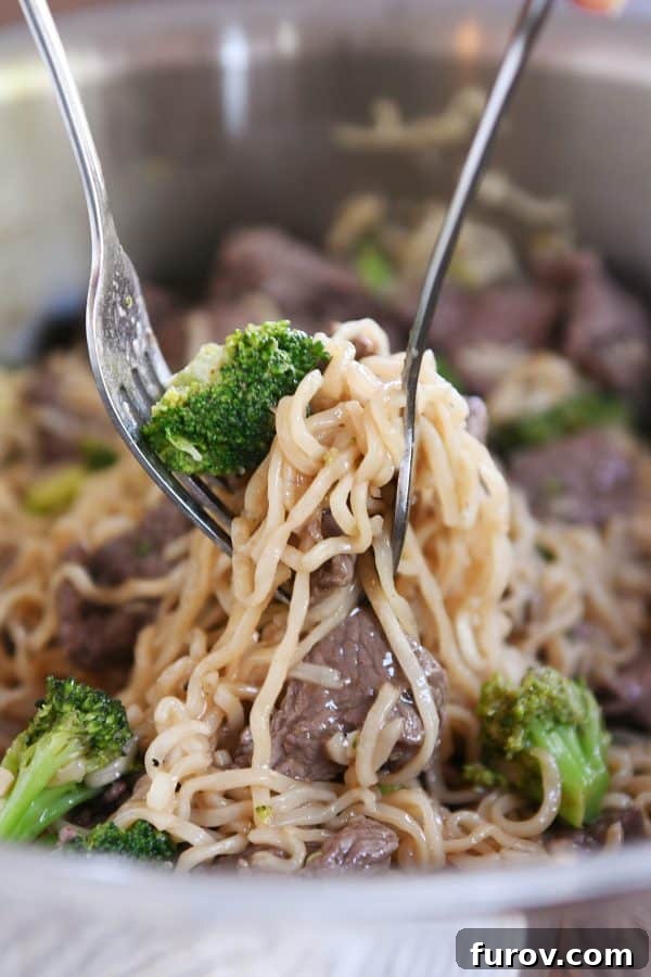 Effortless Beef and Broccoli Ramen Skillet 2 Lifting up ramen noodles with beef and broccoli out of pot with one fork. A vibrant, quick, and easy one-pot beef and broccoli ramen recipe.