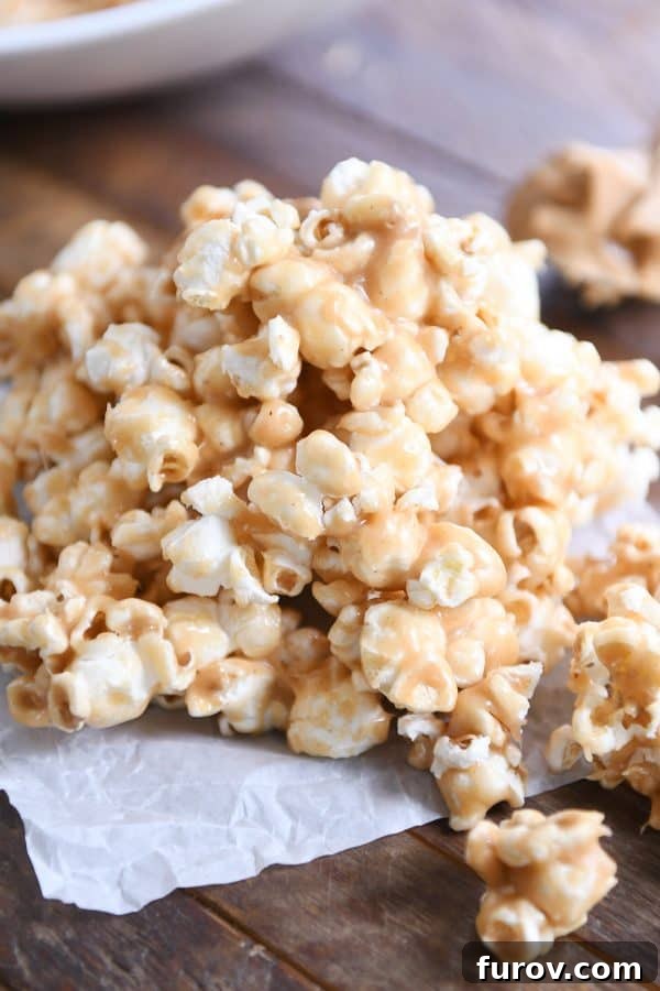 Gooey Peanut Butter Popcorn 11 A generous pile of soft and chewy peanut butter caramel popcorn spread out on wax paper, ready for snacking or sharing.