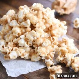 Gooey Peanut Butter Popcorn 12 A generous pile of soft and chewy peanut butter caramel popcorn on wax paper, highlighting its delicious texture and coating, perfect for snacking.