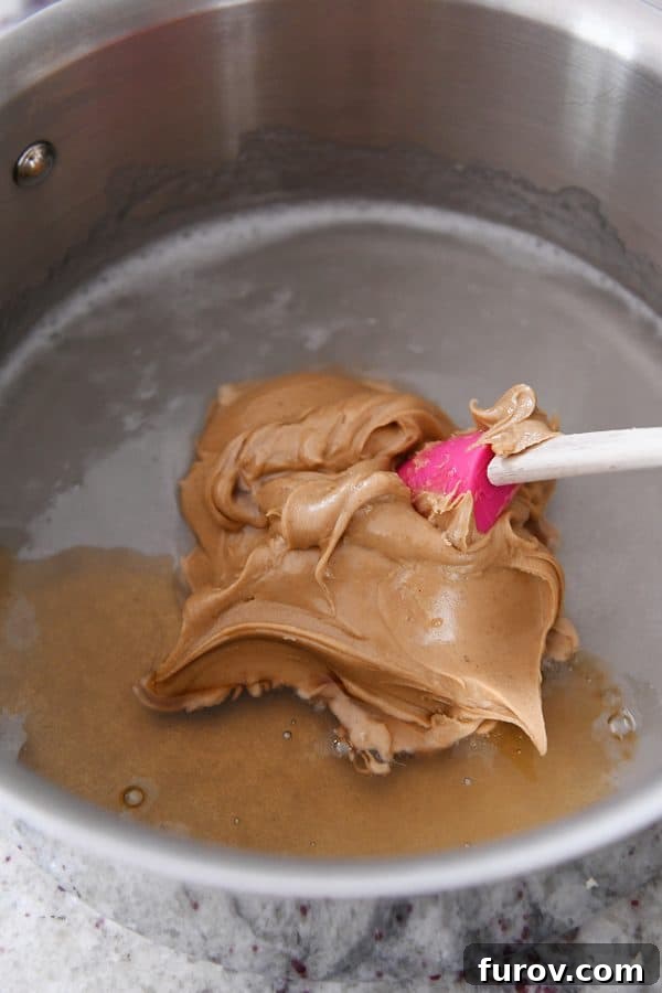 Gooey Peanut Butter Popcorn 7 Peanut butter and vanilla extract freshly added to the warm corn syrup and sugar mixture in a saucepan, ready to be stirred into a luscious caramel sauce.