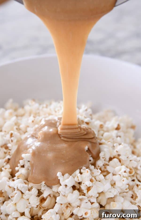 Gooey Peanut Butter Popcorn 9 The moment of transformation: warm, creamy peanut butter caramel mixture being carefully poured and drizzled over a large bowl of fluffy popcorn.