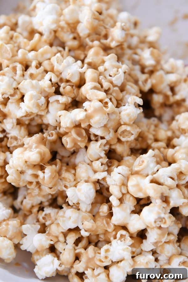 Gooey Peanut Butter Popcorn 10 A detailed close-up of the finished soft and chewy peanut butter caramel popcorn, showcasing its even coating and tempting texture after tossing.