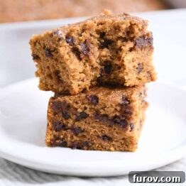 Two pieces of pumpkin chocolate chip snack cake stacked with a bite taken out.