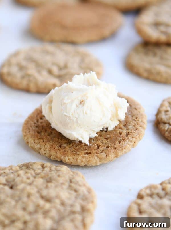A single baked oatmeal cookie with a generous dollop of vanilla frosting on top, ready for its match.
