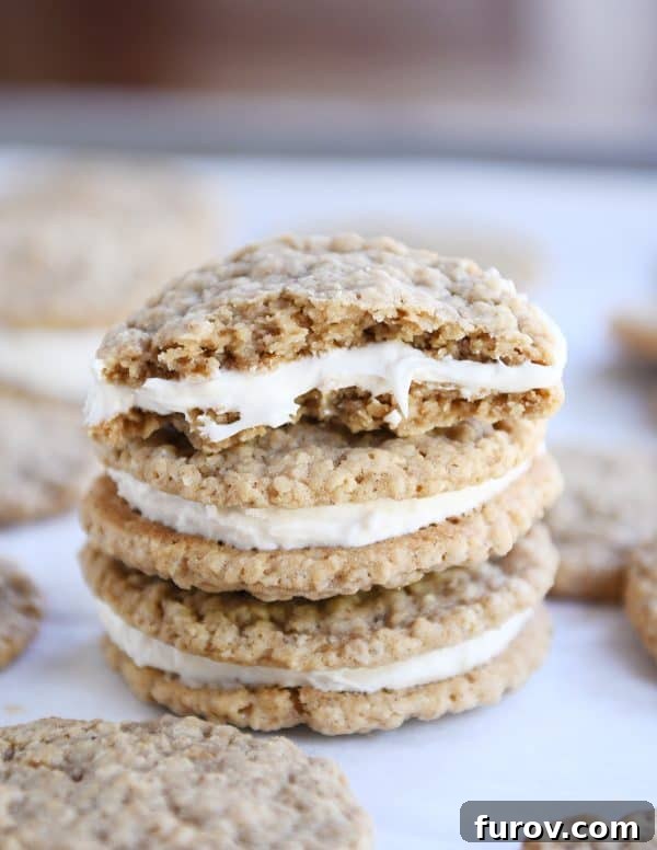 Two homemade oatmeal cream pies stacked on each other with half of a cookie on top, showcasing the inviting filling.