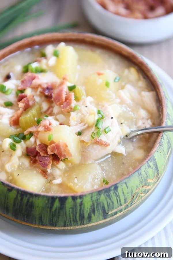 A vibrant green bowl filled with creamy Pressure Cooker Chicken Corn Chowder, topped with crispy bacon bits and fresh chives, with a spoon resting invitingly on the side.