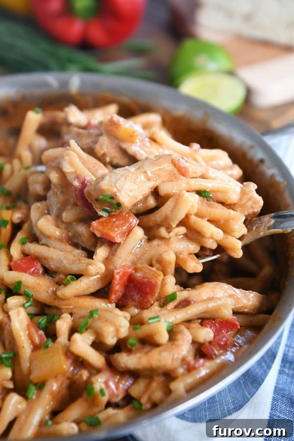 Fiesta Skillet Chicken Fajita Pasta 2 Scooping out spoonful of skillet chicken fajita pasta, showcasing its creamy texture and colorful ingredients.