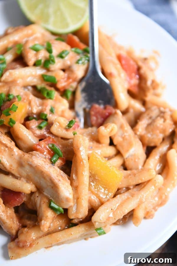 Fiesta Skillet Chicken Fajita Pasta 3 Skillet chicken fajita pasta served on a white plate, ready to be enjoyed with a fork digging in.