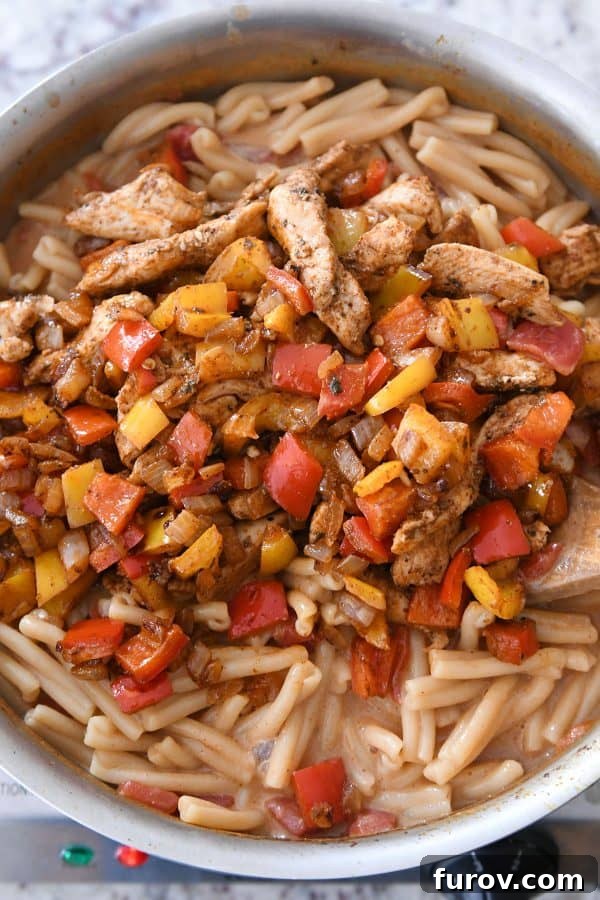 Fiesta Skillet Chicken Fajita Pasta 8 Chicken and vegetables being combined with the creamy pasta in the skillet.