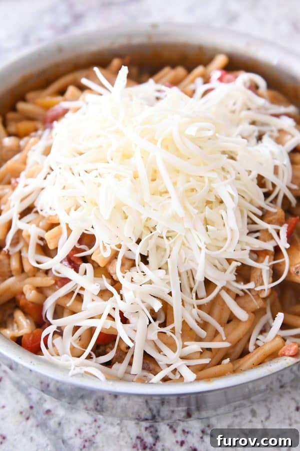 Fiesta Skillet Chicken Fajita Pasta 10 Shredded Monterey Jack cheese being added to the hot skillet chicken fajita pasta, ready to melt into creamy perfection.