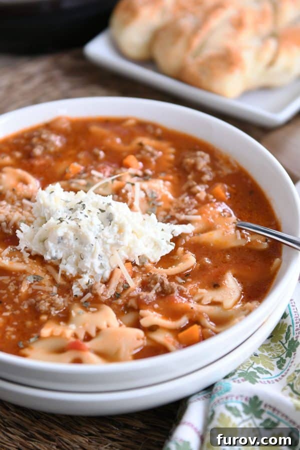 Homemade Lasagna Soup Pressure Cooker or Stovetop 3 A beautifully presented white bowl brimming with hearty pressure cooker lasagna soup, topped with a generous dollop of creamy, cheesy ricotta mixture.