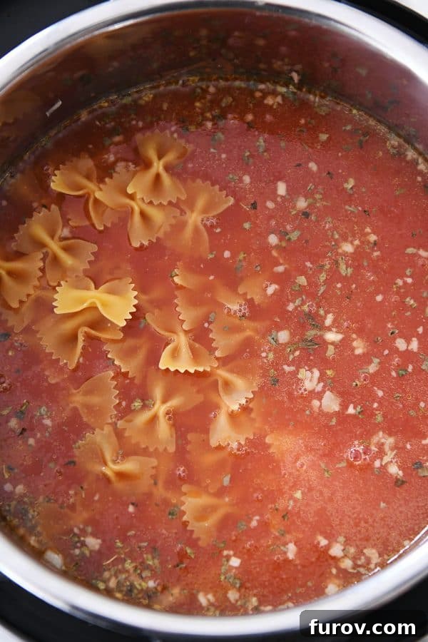 Homemade Lasagna Soup Pressure Cooker or Stovetop 5 A pressure cooker filled with savory ingredients, with pasta and broth being added for the delicious lasagna soup.