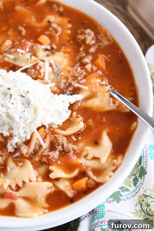 Homemade Lasagna Soup Pressure Cooker or Stovetop 8 A top-down view of a white bowl filled with pressure cooker lasagna soup, generously adorned with a dollop of cheesy ricotta mixture, inviting a delightful meal.