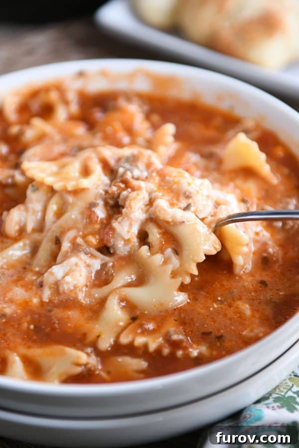 Homemade Lasagna Soup Pressure Cooker or Stovetop 9 A spoonful being taken from a white bowl of pressure cooker lasagna soup, showing the rich texture and cheese topping.