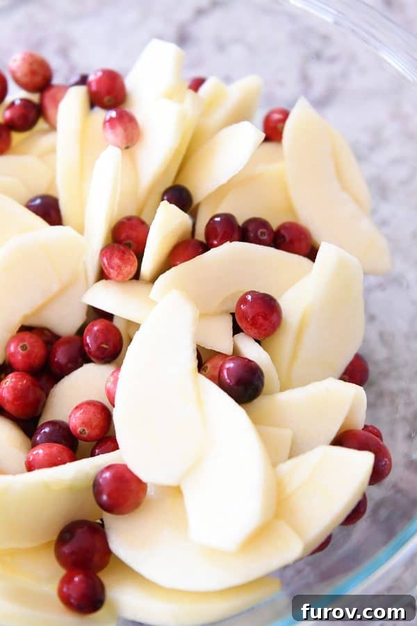 My Favorite Thanksgiving Apple Cranberry Pie 5 Glass bowl with sliced apples and fresh cranberries.