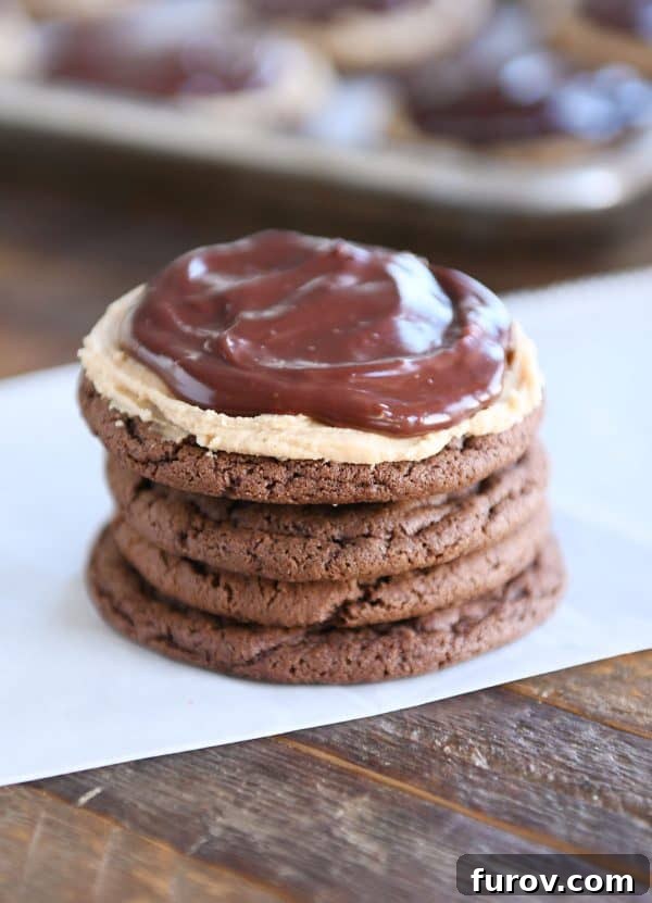 Stack of four chocolate peanut butter buckeye cookies, perfectly frosted and ganache-d.
