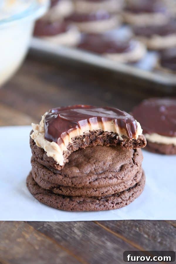 A stack of chocolate peanut butter buckeye cookies, with the top cookie having a bite taken out, showcasing its delicious layers.