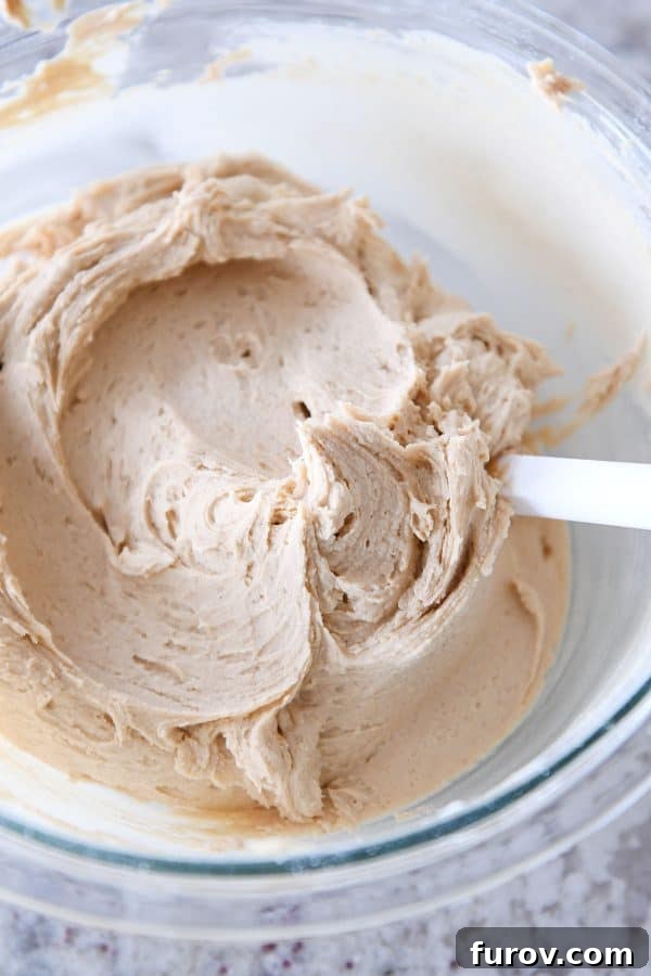 A bowl of rich, creamy peanut butter frosting, smooth and ready for application.