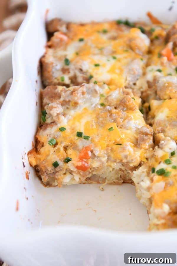 A pan of baked tater tot breakfast casserole with one square neatly removed, showing the fluffy interior.