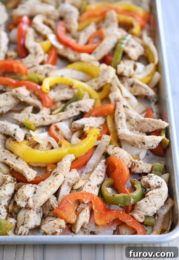 One-Pan Chicken Fajitas 2 Sheet pan loaded with colorful bell peppers and tender chicken strips, ready for easy sheet pan chicken fajitas.