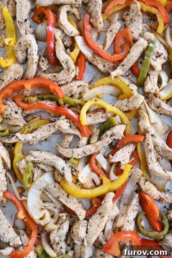 One-Pan Chicken Fajitas 4 Another view of a sheet pan generously loaded with colorful bell peppers and seasoned chicken strips, ready for the oven to create easy sheet pan chicken fajitas.