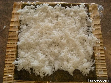 White sushi rice spread thinly and evenly across the entire surface of the nori sheet, covering it from edge to edge.