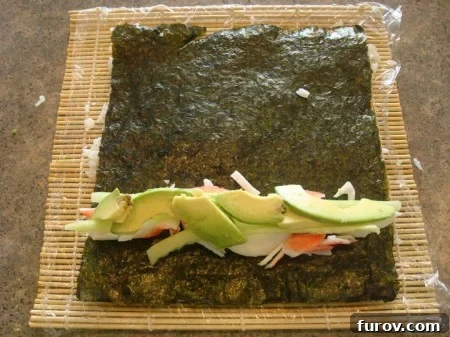 Creamy avocado slices carefully placed on top of the cucumber and crab, completing the main filling for the sushi roll.