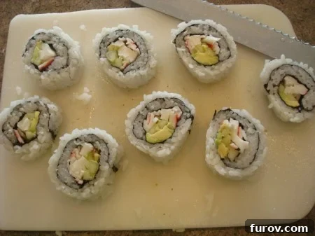 Eight perfectly sliced pieces of California sushi roll arranged neatly on a white cutting board, ready for serving.