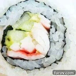 A vibrant California sushi roll with rice on the outside, filled with avocado, cucumber, and crab.