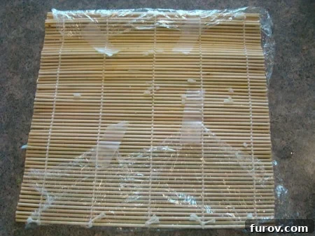 The bamboo mat with plastic wrap securely taped on the underside, ensuring a smooth rolling surface.