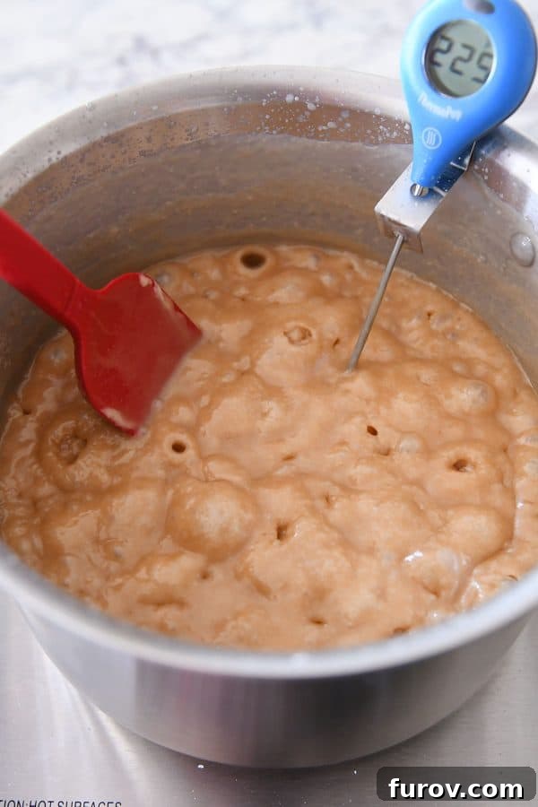 Close-up of bubbling caramel in a metal pot, illustrating the crucial cooking stage.